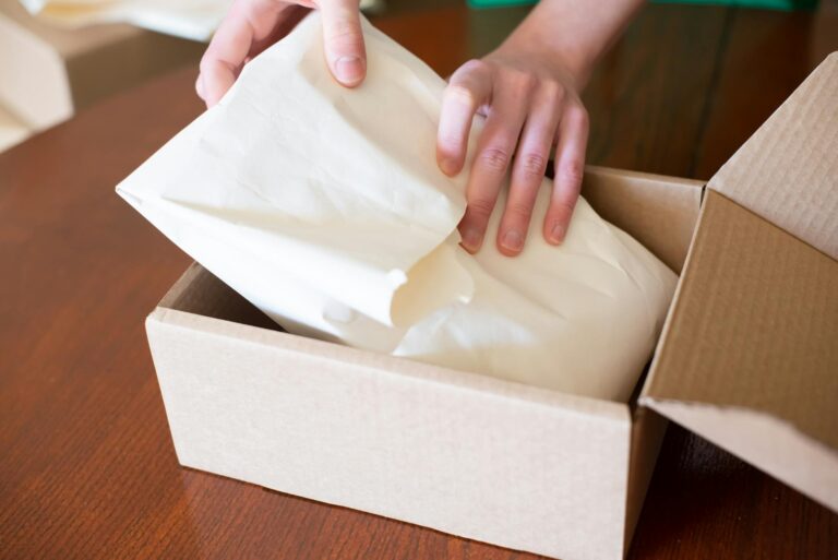 Hands wrapping merchandise in a cardboard box for shipping, ideal for small business stock images.